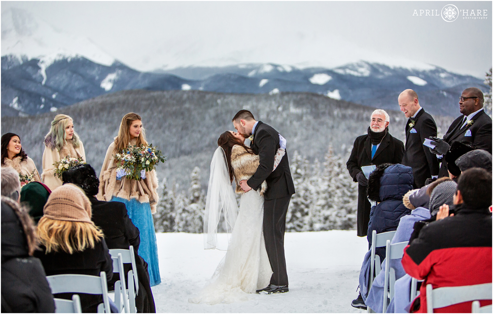 Bride and groom kiss at the end of their winter wedding ceremony at Anticipation run at Keystone Resort in CO