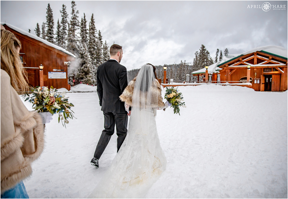 Bride and groom walk to their reception at Alpenglow Stube at Keystone Resort on their winter wedding day in CO