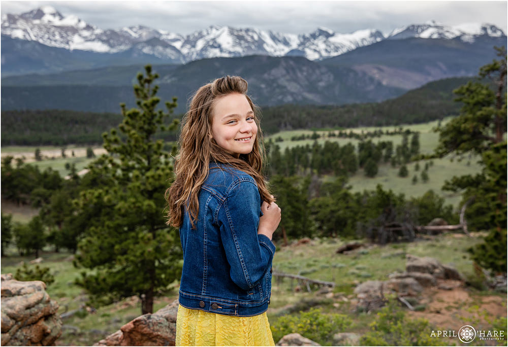 12 year old girl in a jean jacket poses for her own photo during family portrait session at RMNP