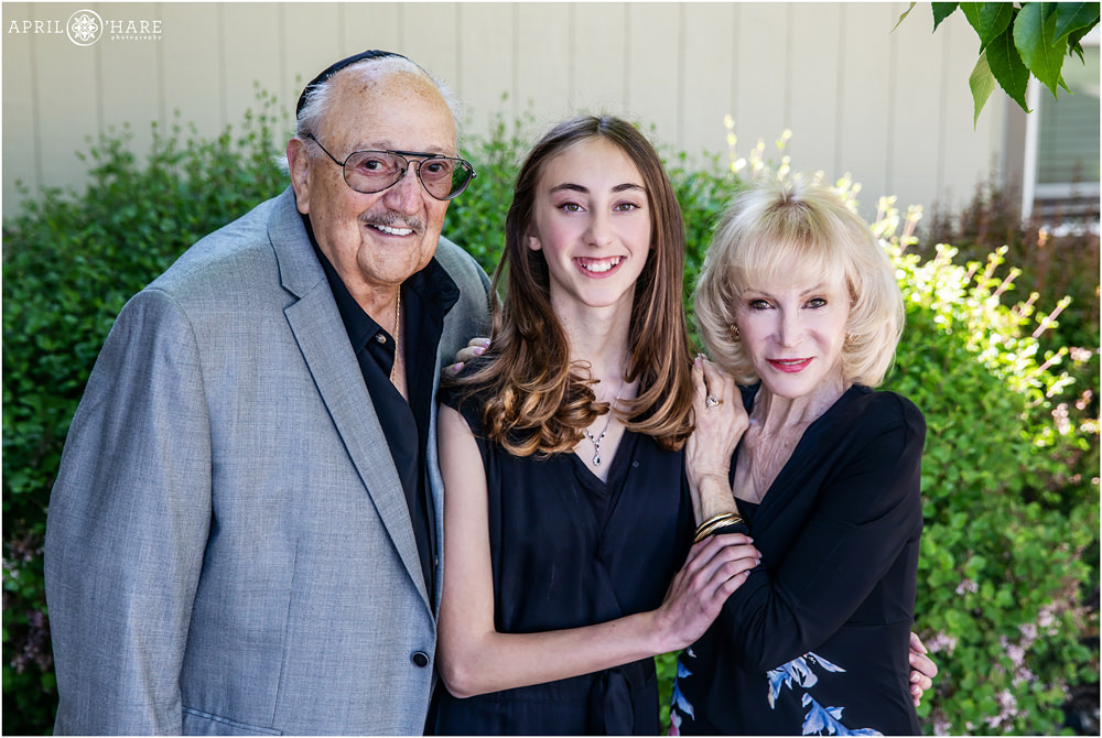 Young bat mitzvah girl and her grandparents pose for a portrait outside of Temple B'Nai Chaim