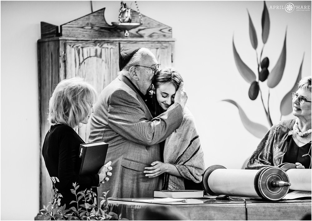 Grandfather kisses his granddaughter at her Bat mitzvah in Denver