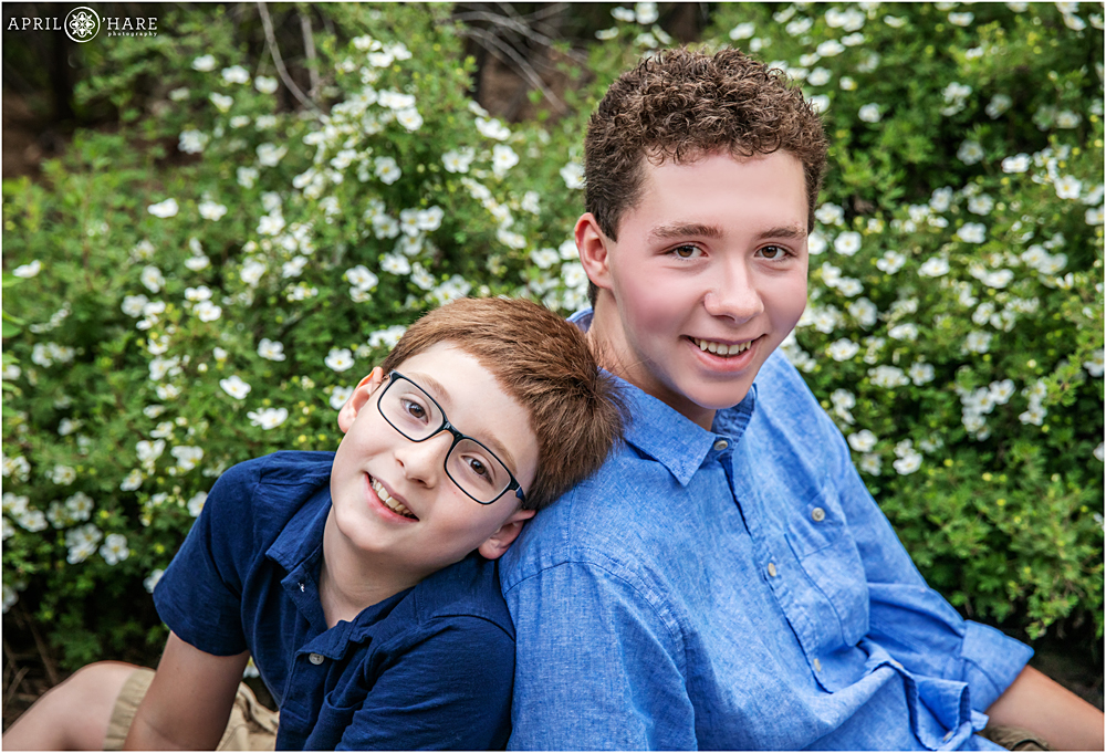 Brothers Pose for a Sibling photo with flowering bush at Hudson Gardens in Littleton, CO