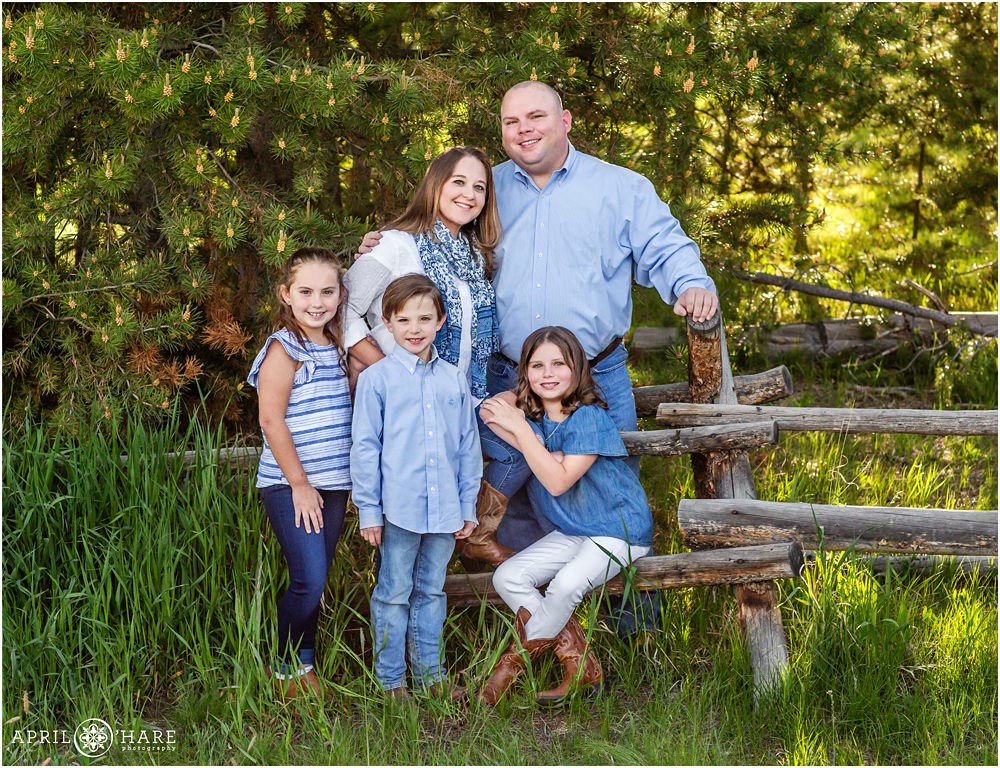 A family poses for pictures on a ranch fence in Summit County Colorado during summer