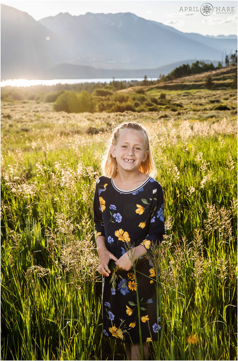 Happy girl smiles for her family picture in the tall grasses at Lake Dillon in Colorado