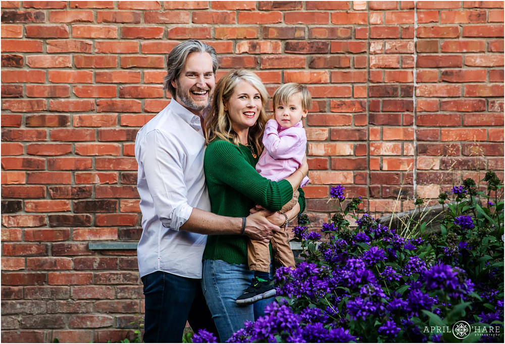 Classic family portrait with an old red brick wall and bright purple flowers in Downtown Telluride Colorado