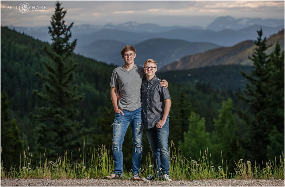 Two brothers pose for a portrait in front of a pretty mountain view at their extended family portraits near Denver