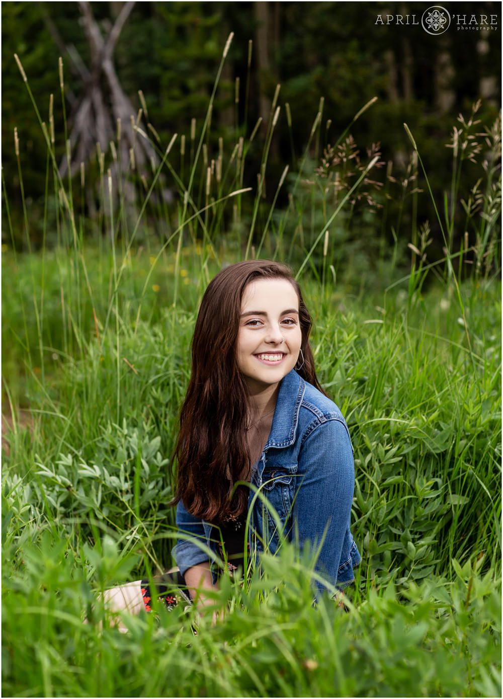 Evergreen Senior Photography in a mountain meadow with a wood tipi in the backdrop