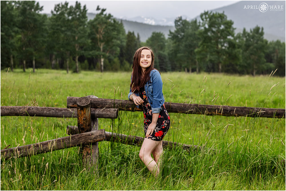 Evergreen Senior Photography with ranch fence and mountain backdrop in Colorado