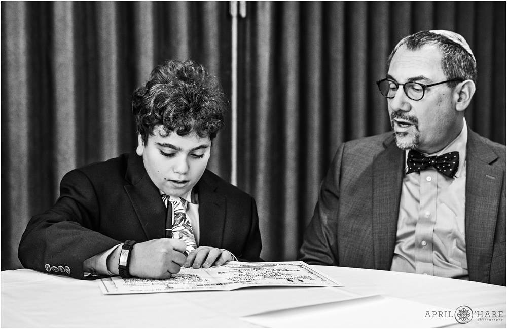 B&W photo of a young boy signing the contract at his bar mitzvah in Denver CO