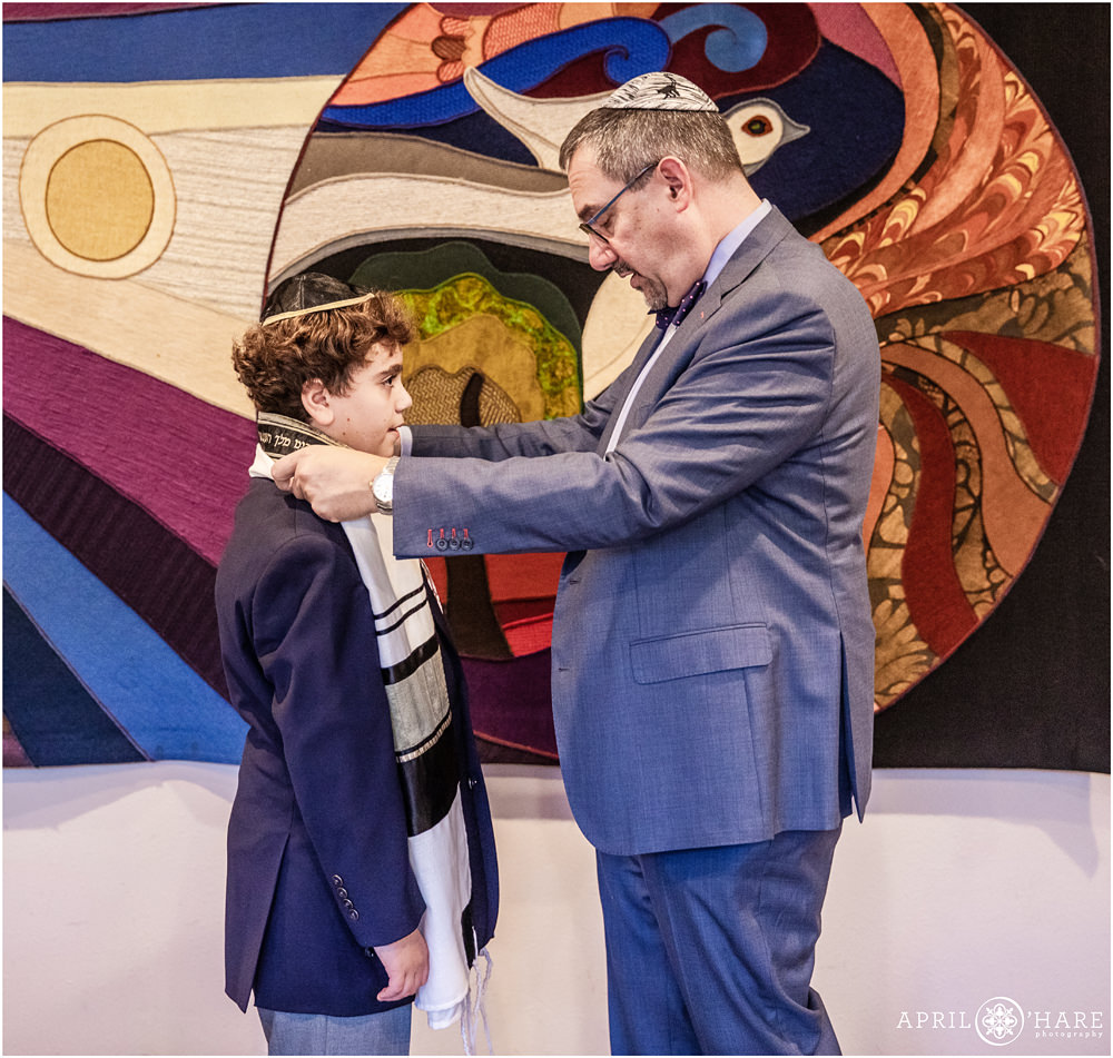 Rabbi at Temple Emanuel helps bar mitzvah boy with his tallit in Denver Colorado