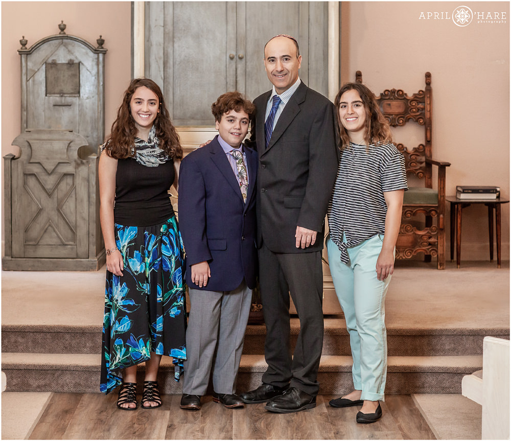 Boy with his dad and sisters pose for a family photo at his Temple Emanuel Bar Mitzvah in Denver