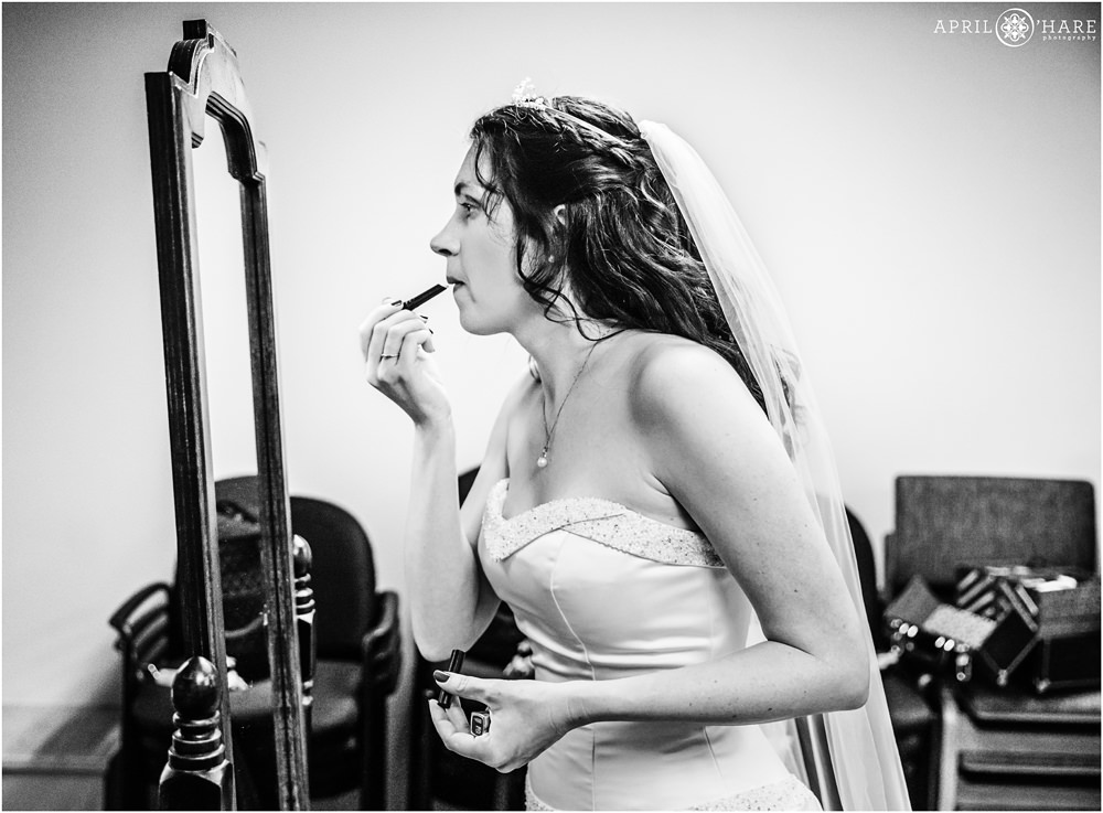B&W photo of a bride putting on her lipstick before her wedding ceremony at Our Father Lutheran Church