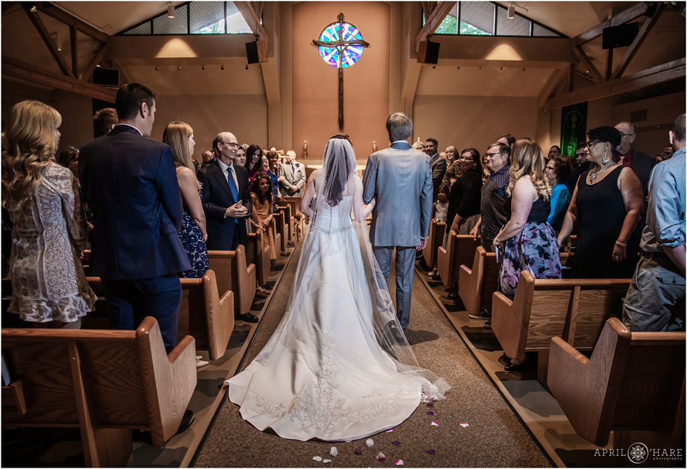 Bride walks down the aisle with her father at Our Father Lutheran Church in Centennial CO
