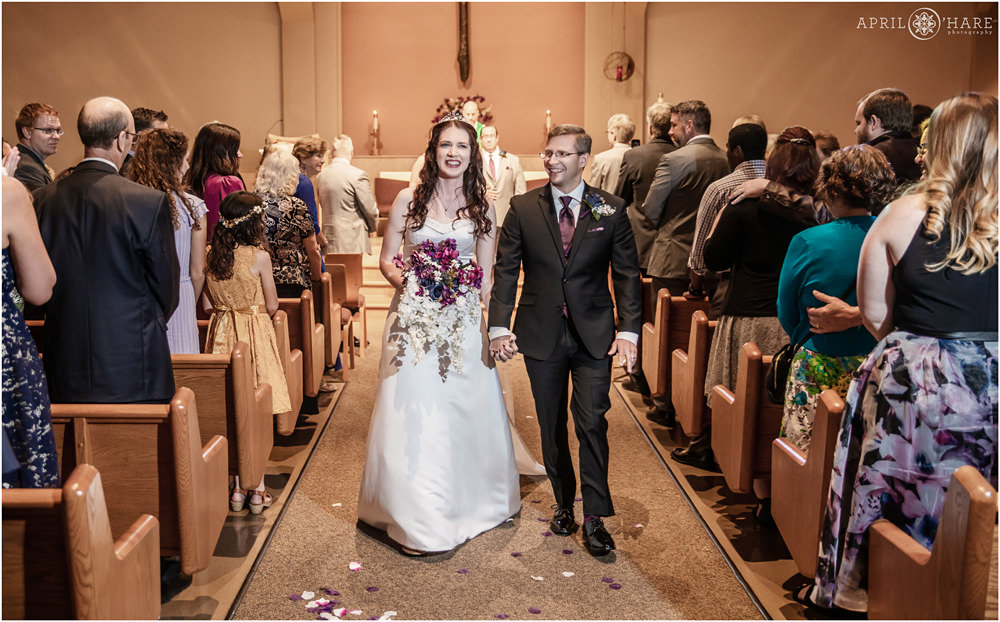 Happy Bride and groom walk down aisle after their wedding at Our Father Lutheran Church in Centennial Colorado