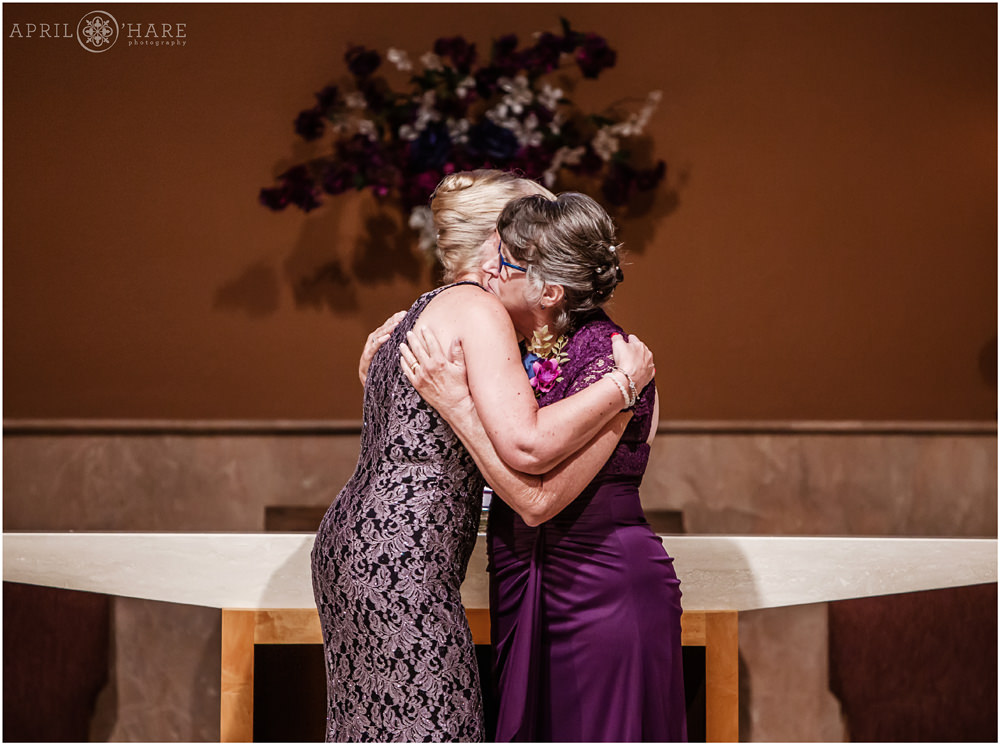 Mother of Bride and Mother of Groom hug after lighting candles Our Father Lutheran Church