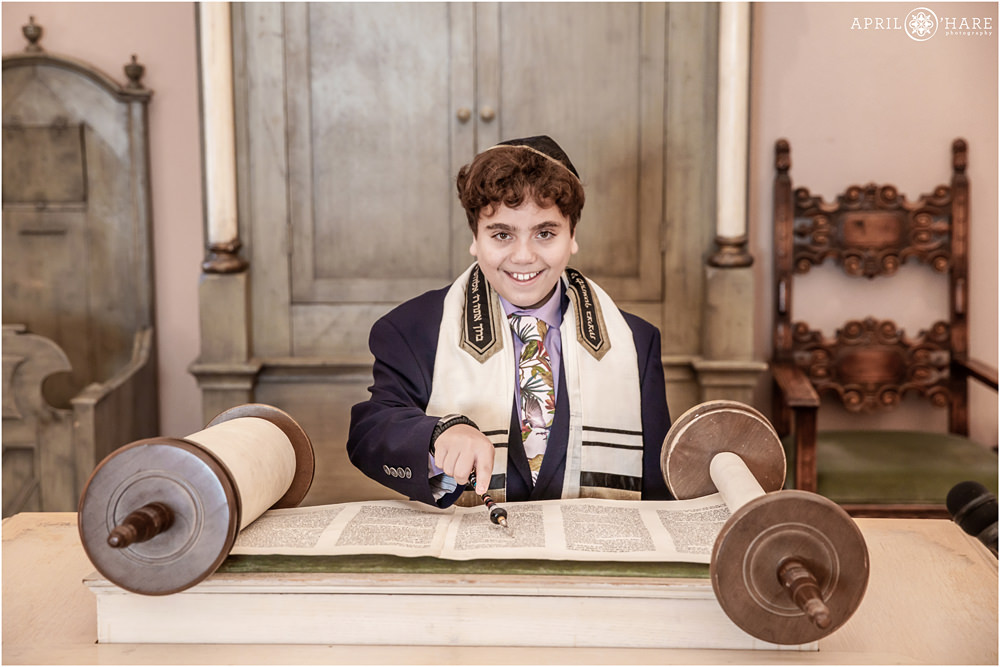 Bar Mitzvah boy smiles as he reads from the torah at his bar mitzvah at Temple Emanuel in Denver Colorado