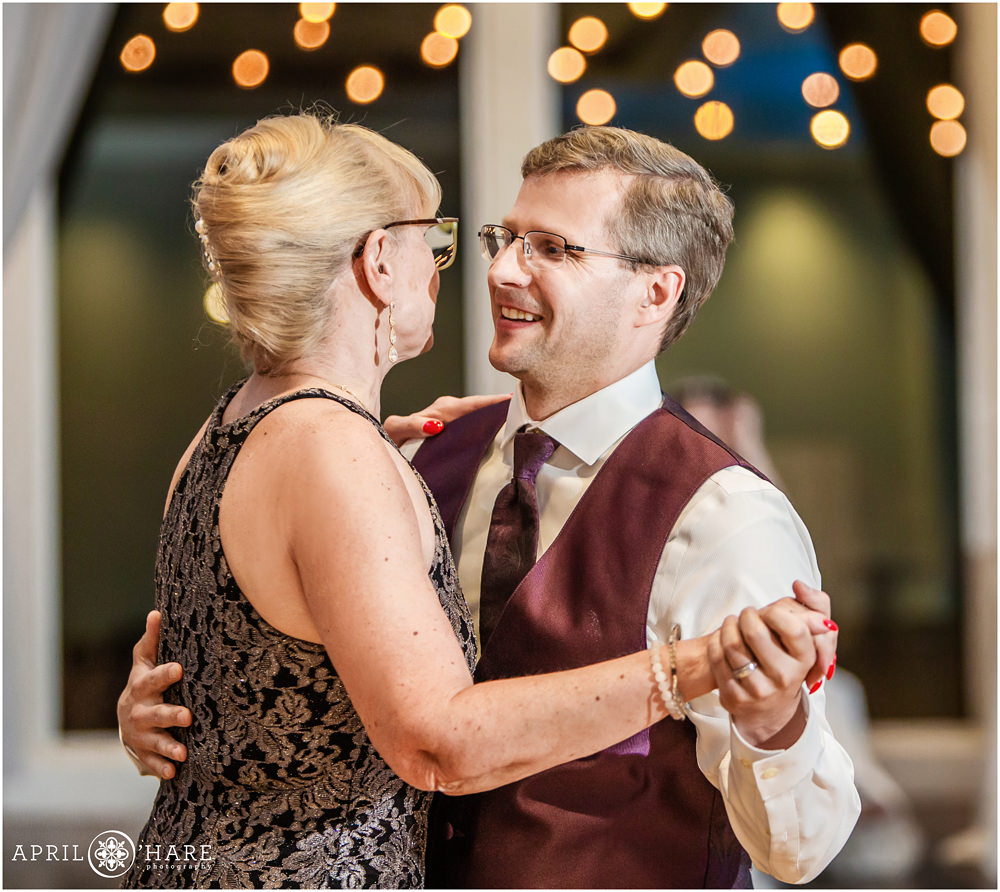 Groom dances with his mom with twinkle light backdrop at his Ashley Ridge Wedding Reception in Littleton