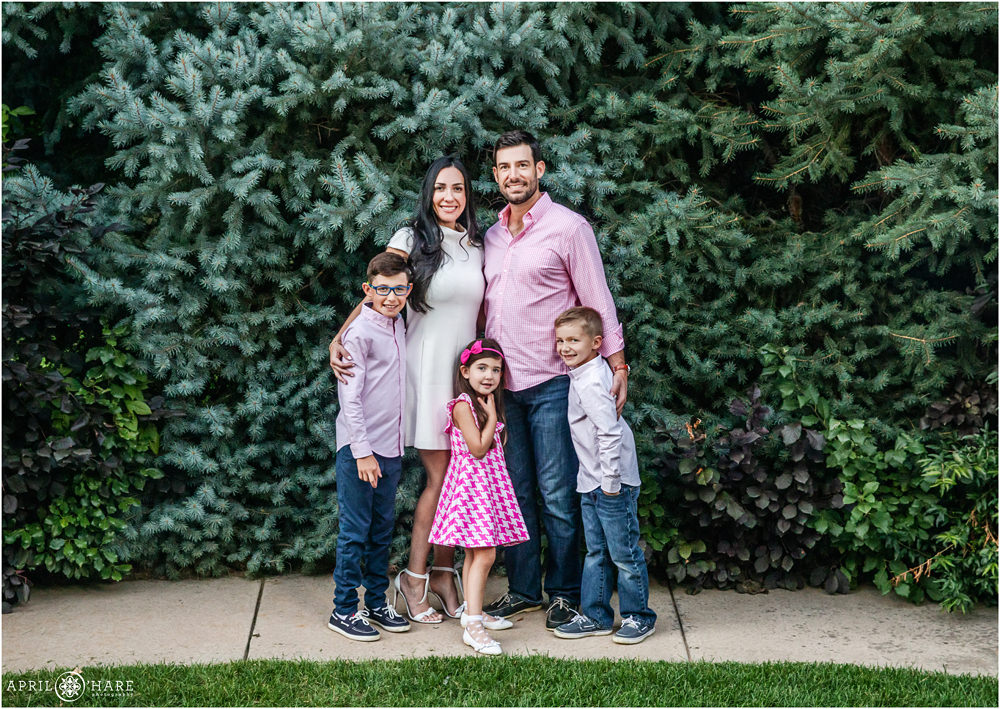 Cute family of 5 wearing pink and white pose for portraits in the backyard at their home in Denver