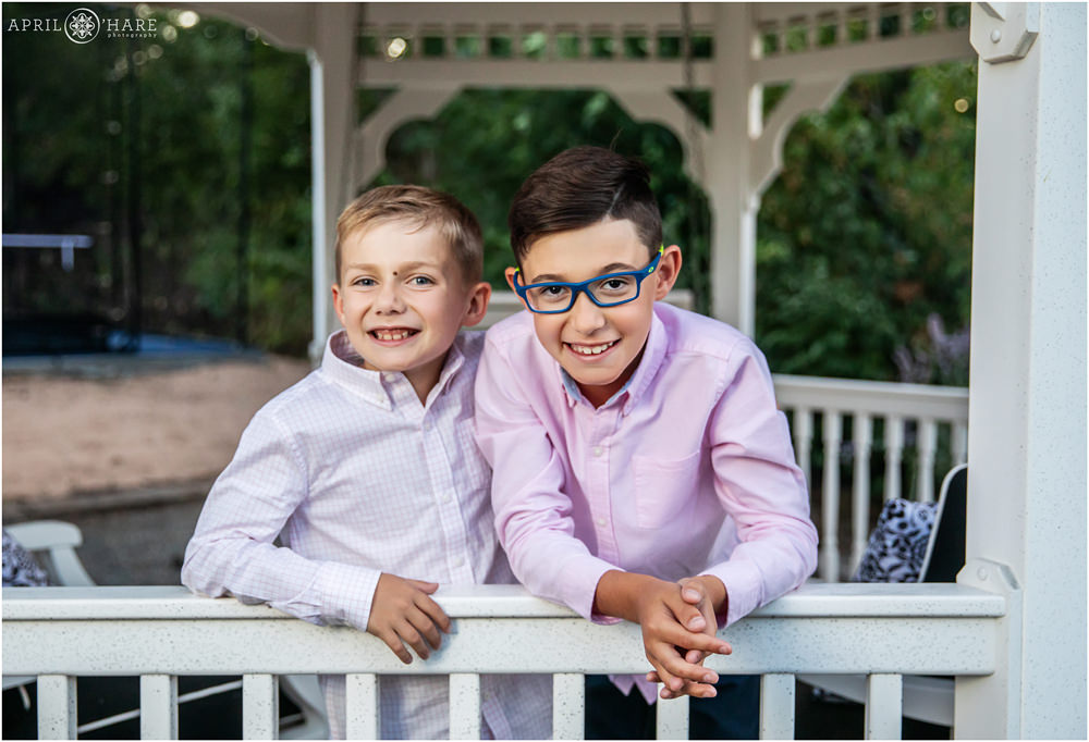 Two young brothers pose for a portrait together in the white gazebo in their backyard at home in Denver