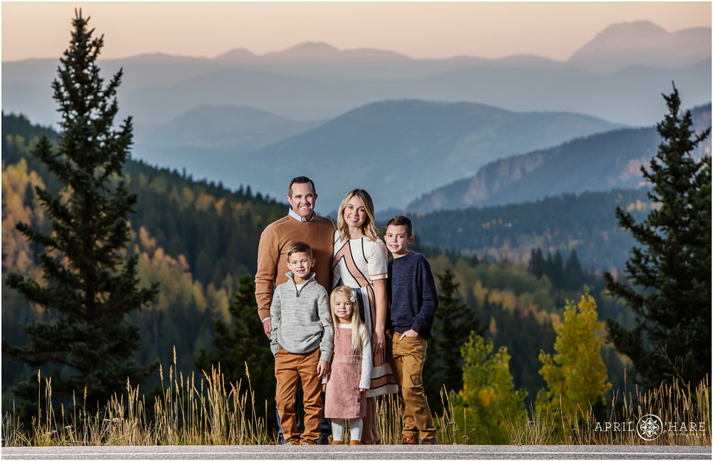 A beautiful family of 5 poses on the side of Squaw Pass Road with a stunning layered mountain view in the distance