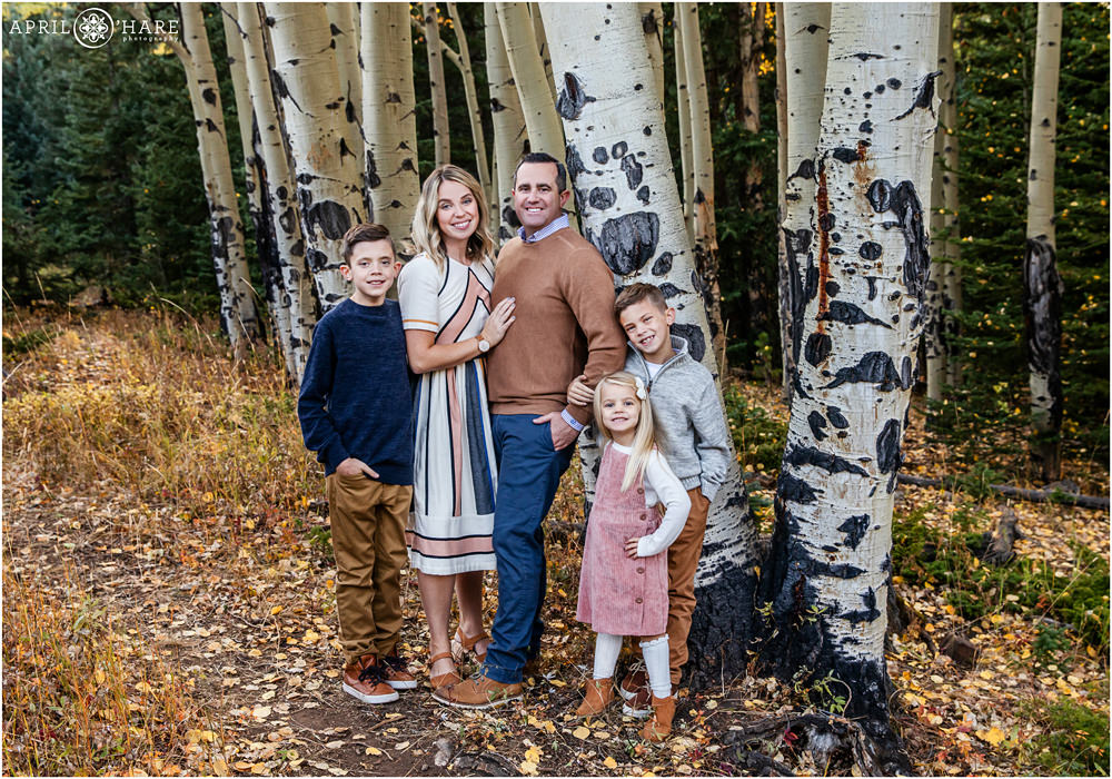 A family of 5 posing with aspen trees for autumn pictures in Colorado on Squaw Pass Road