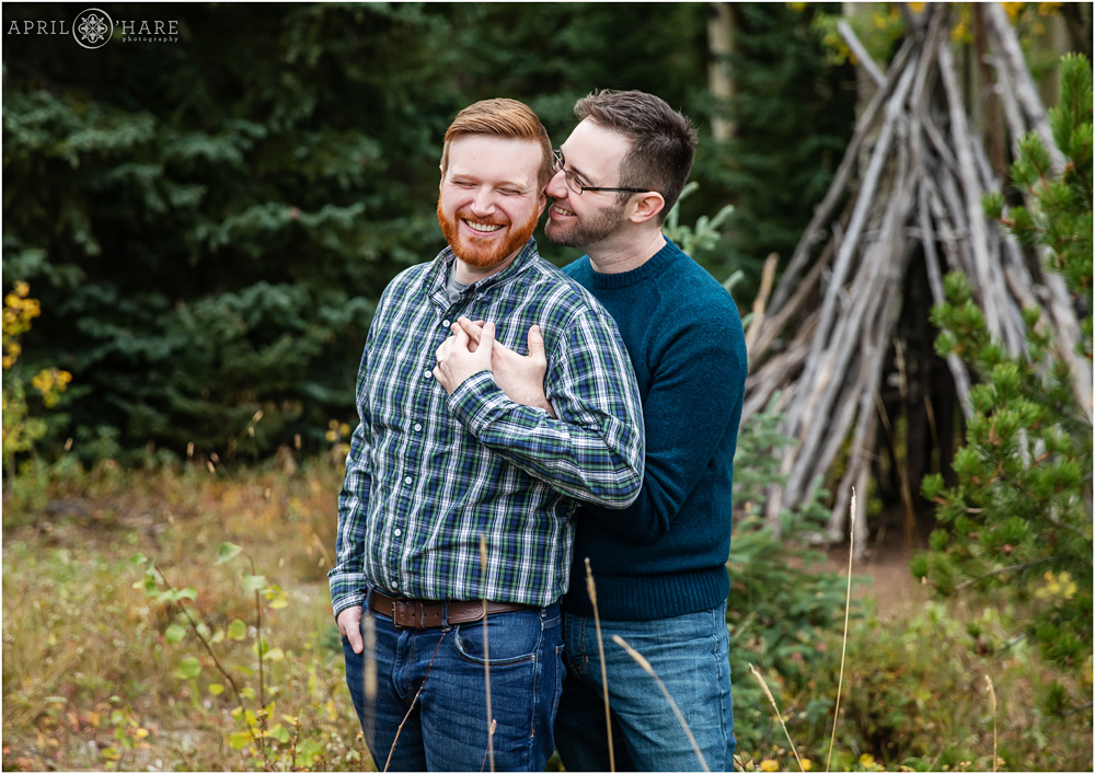 Happy moment of two men laughing together at their Colorado fall color engagement session in the mountains