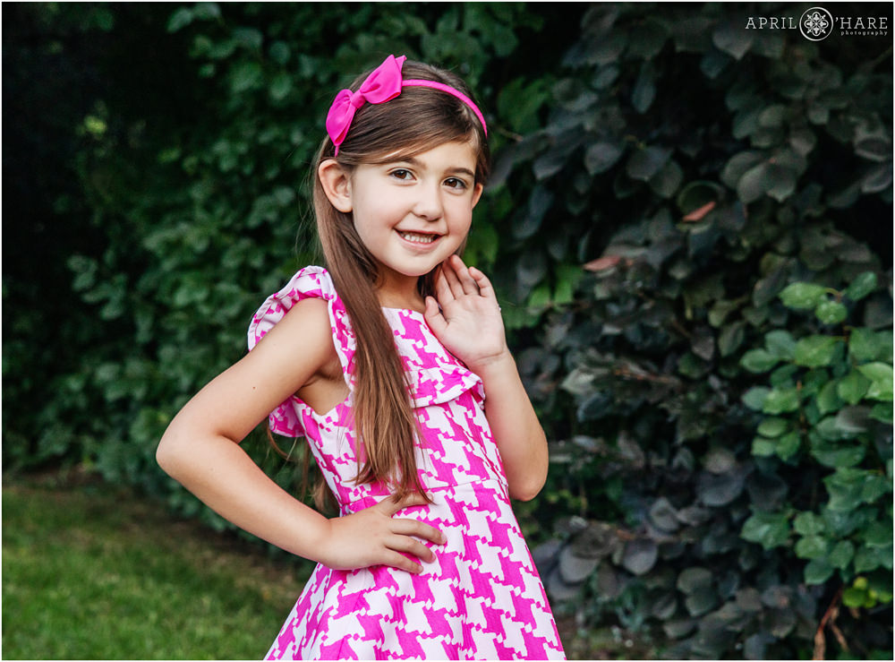 Cute little girl wearing pink poses for a picture by herself during family pictures at home in Denver