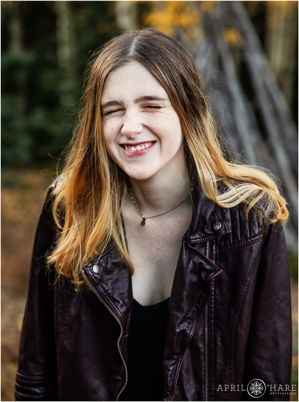Cute photo of a senior girl laughing with her eyes closed on Squaw Pass Road in Evergreen Colorado