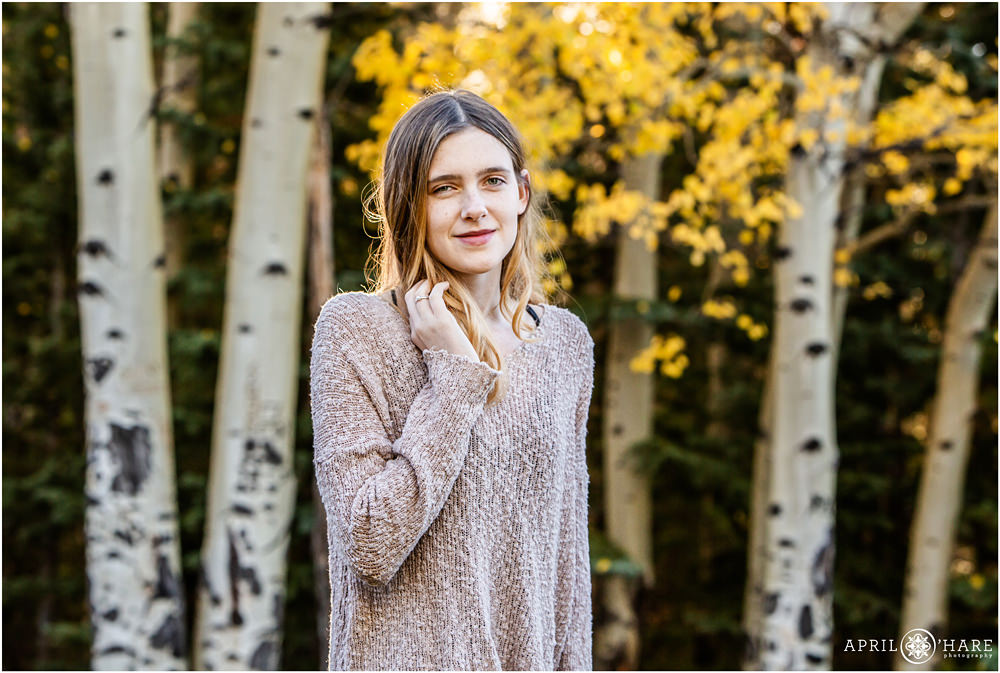 Soft smile on a high school senior girl with pretty aspen tree backdrop on Squaw Pass Road in Colorado