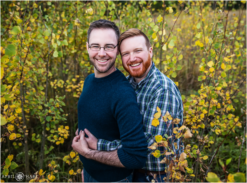 Happy gay engagement photo surrounded by fall color in Colorado