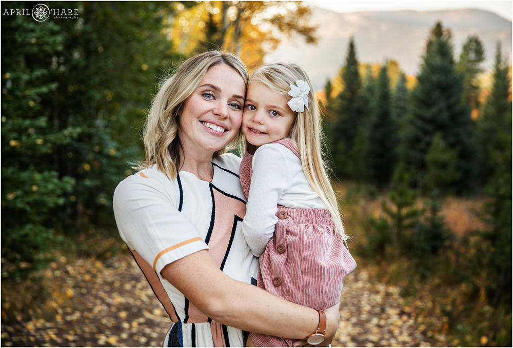Cute photo of a mama with her young daughter in her arms with pretty autumn backdrop in Colorado