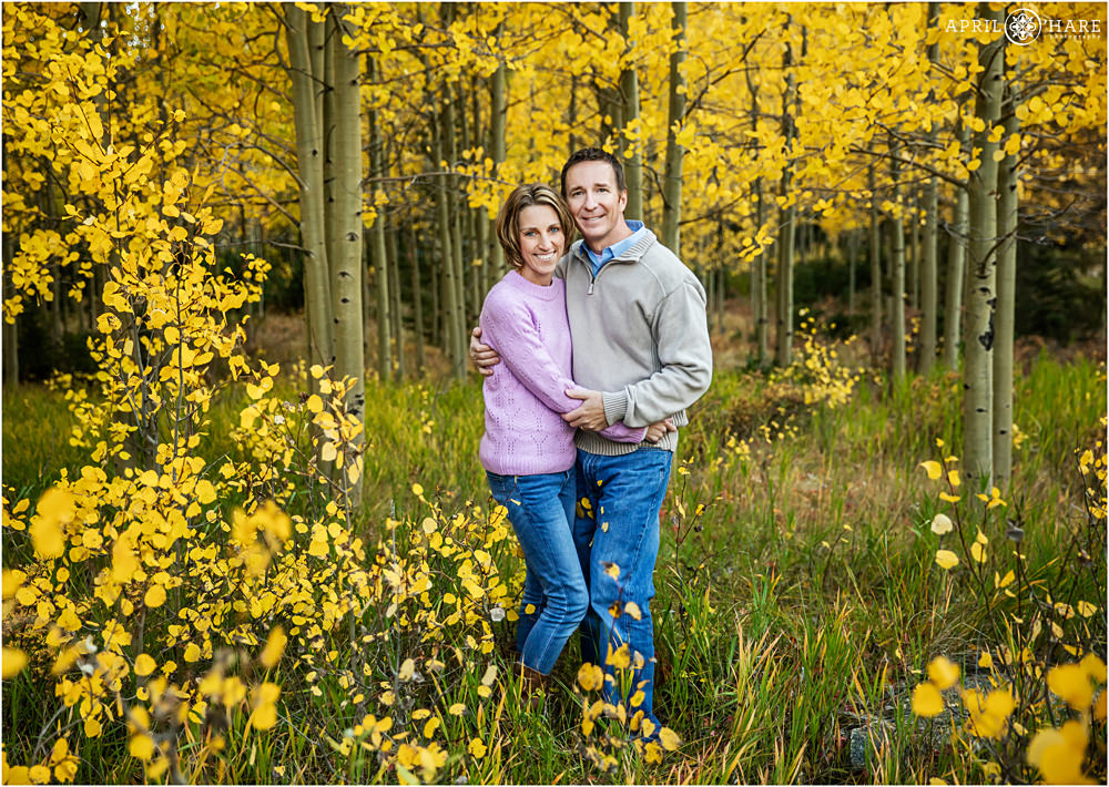 Parents pose for a couples photo in the yellow aspen leaves while wearing lilac on Guanella Pass