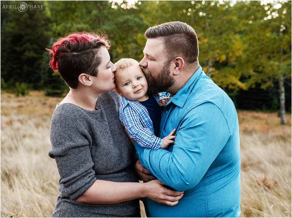 Parents kiss their sweet baby boy in a pretty fall color mountain meadow in Colorado