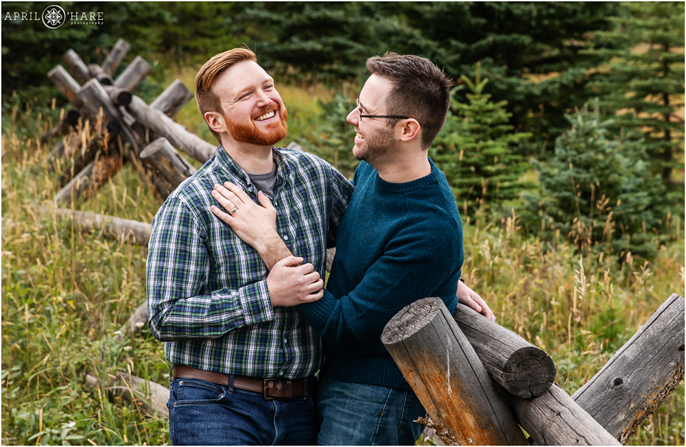Having fun at a Colorado mountain engagement photography session next to a rustic wood fence on Squaw Pass Road