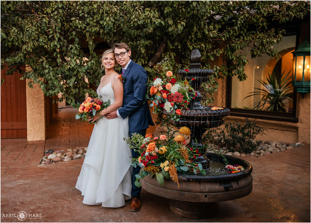 Gorgeous Fall Color Orange Florals Decorate Fountain in Courtyard for a pretty dusk wedding portrait at Villa Parker