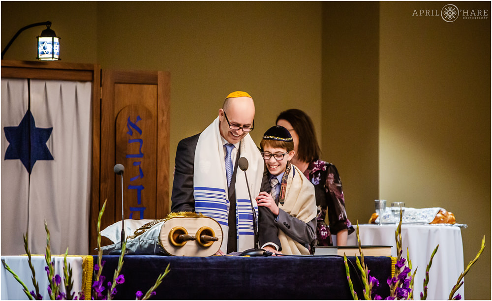 Boy laughs with his dad during a speech during his bar mitzvah service at The Lincoln Center in Fort Collins Colorado