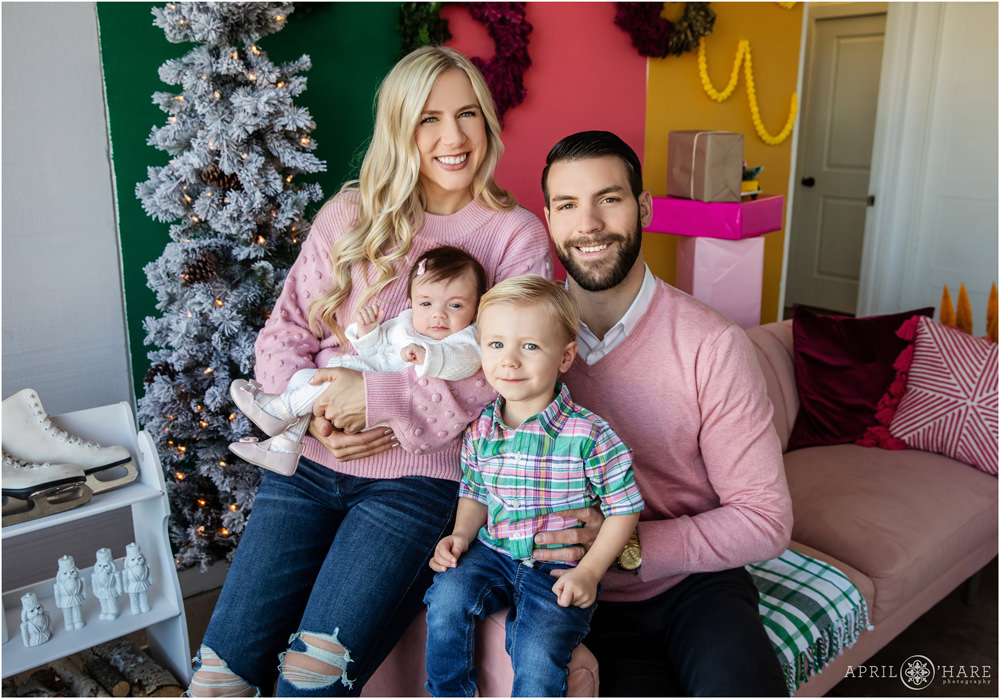 Cute family of four wearing pink and green for their colorful holiday family portraits in a Denver studio