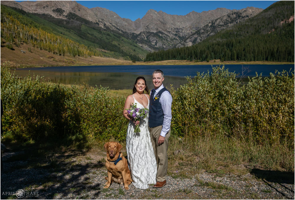 A bride and groom pose for a photo with their dog at Piney River Ranch