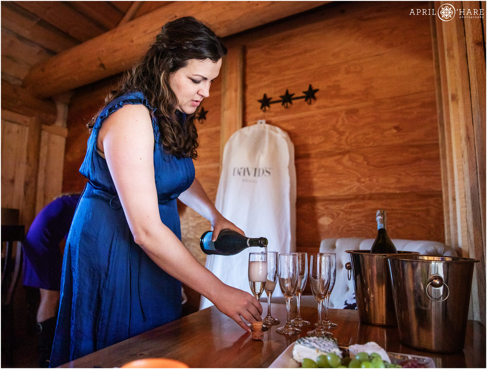 Bridesmaid pours some champagne at Piney River Ranch in Vail