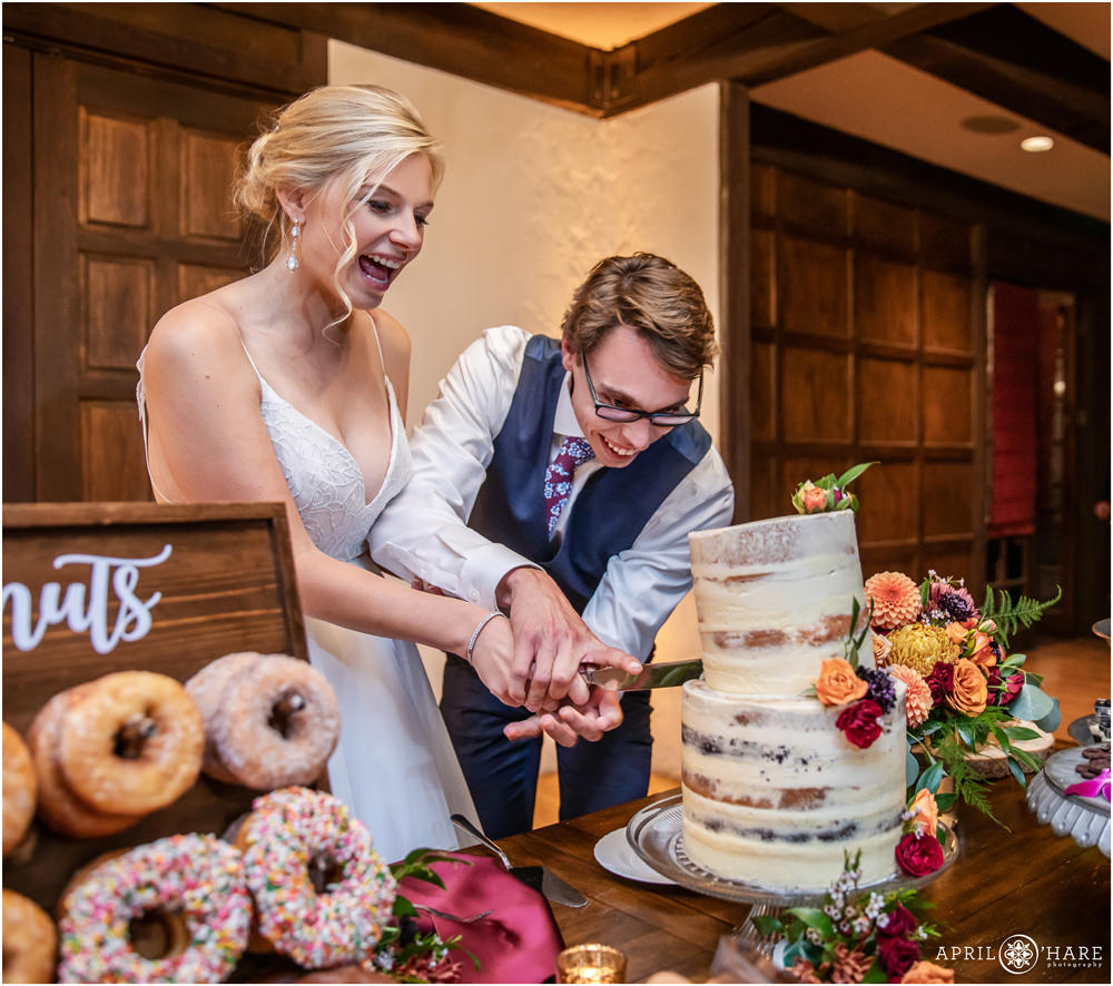 Bride and groom laugh as they cut their naked wedding cake by Posh Cakes at Villa Parker in Colorado