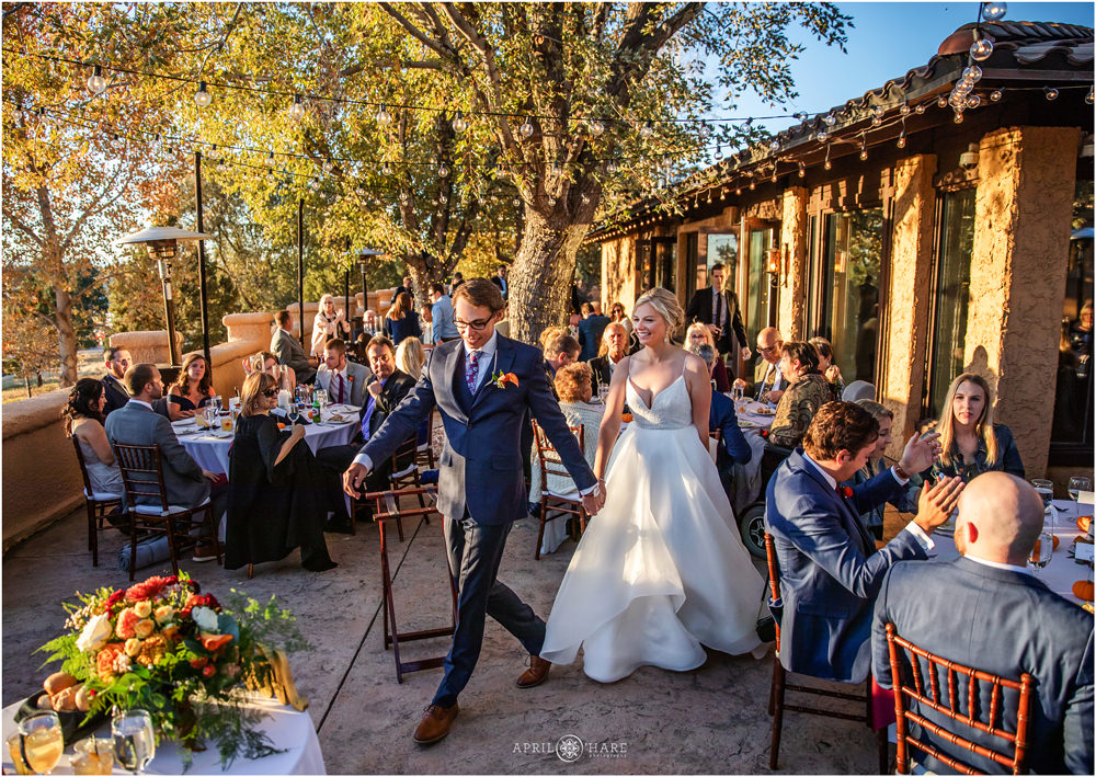 Bride and groom walk into their outdoor wedding reception on the patio on a fall wedding day at Villa Parker