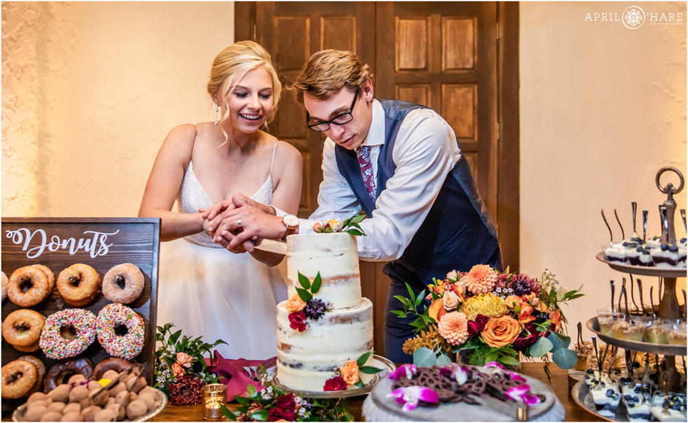 Bride and groom have fun cutting their cute naked cake by Posh Cakes at Villa Parker in Colorado