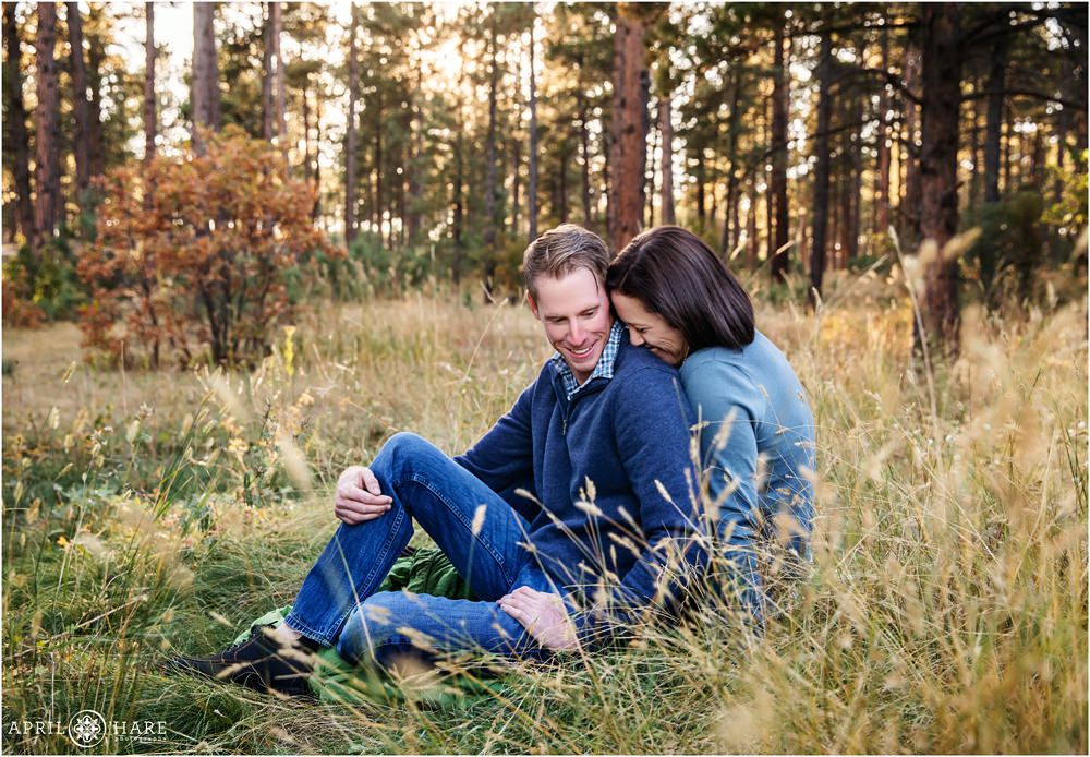 Engaged couple snuggle in a pine tree forest at Fox Run Regional Park in Colorado Springs