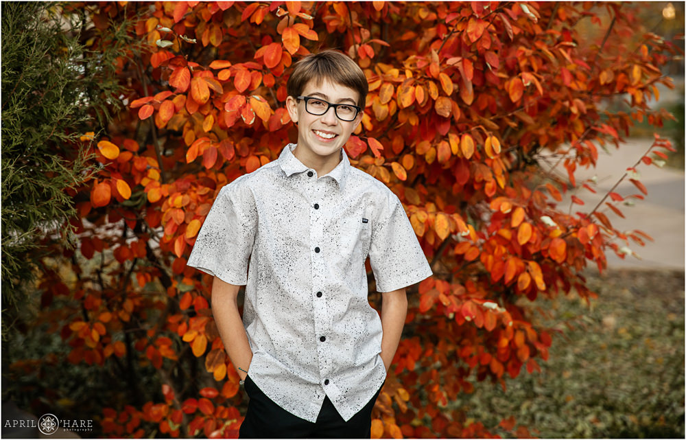 A casual portrait of a bar mitzvah boy with pretty orange autumn leaves backdrop outside of the Lincoln Center in Fort Collins Colorado