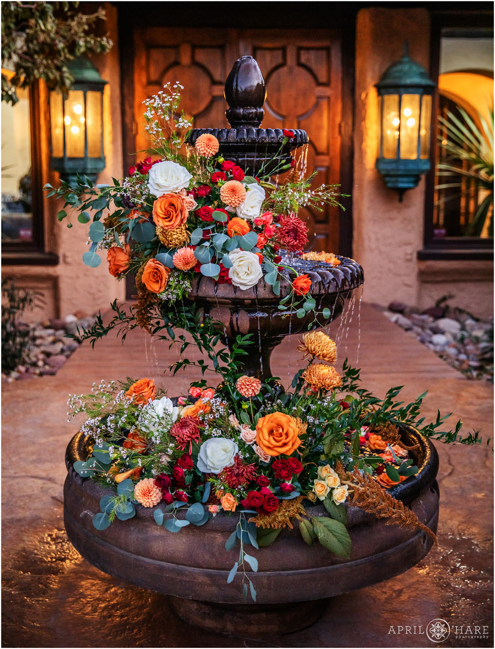 Gorgeous orange flowers decorate the courtyard fountain at Villa Parker at dusk by Project Floral during Autumn Wedding in Colorado