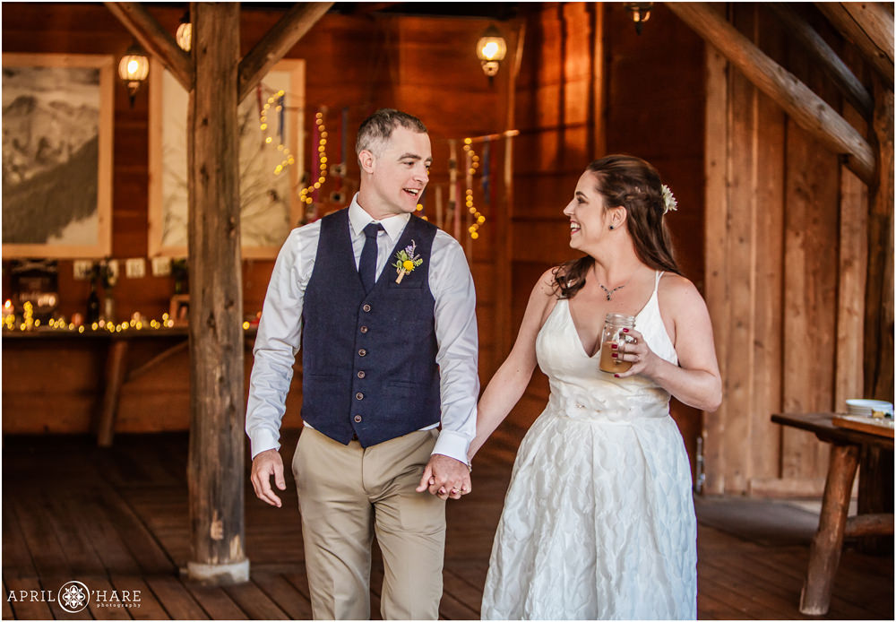 Bride and groom walk into their rustic wedding reception in Vail holding hands