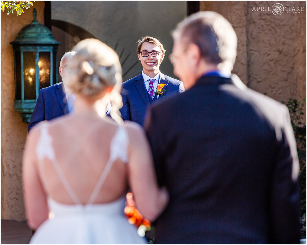 Groom smiles at his bride as she walks down the aisle toward him at Villa Parker