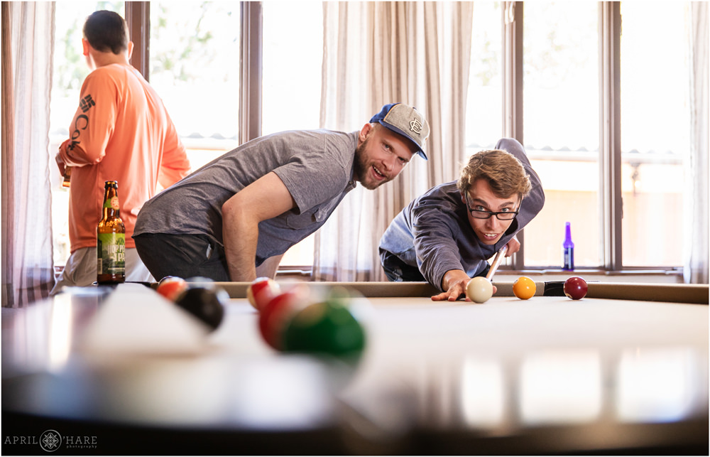 Groom and his friend play pool at Villa Parker on his wedding day in Colorado