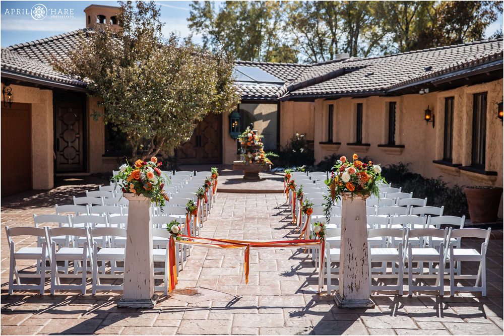Beautiful outdoor ceremony set up with orange decor and fall color flowers by Project Floral at Villa Parker in Colorado