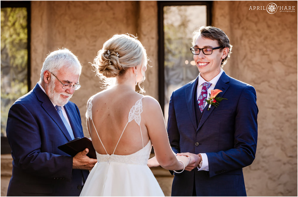 Happy groom smiles at his bride during their outdoor courtyard wedding at Villa Parker in Colorado